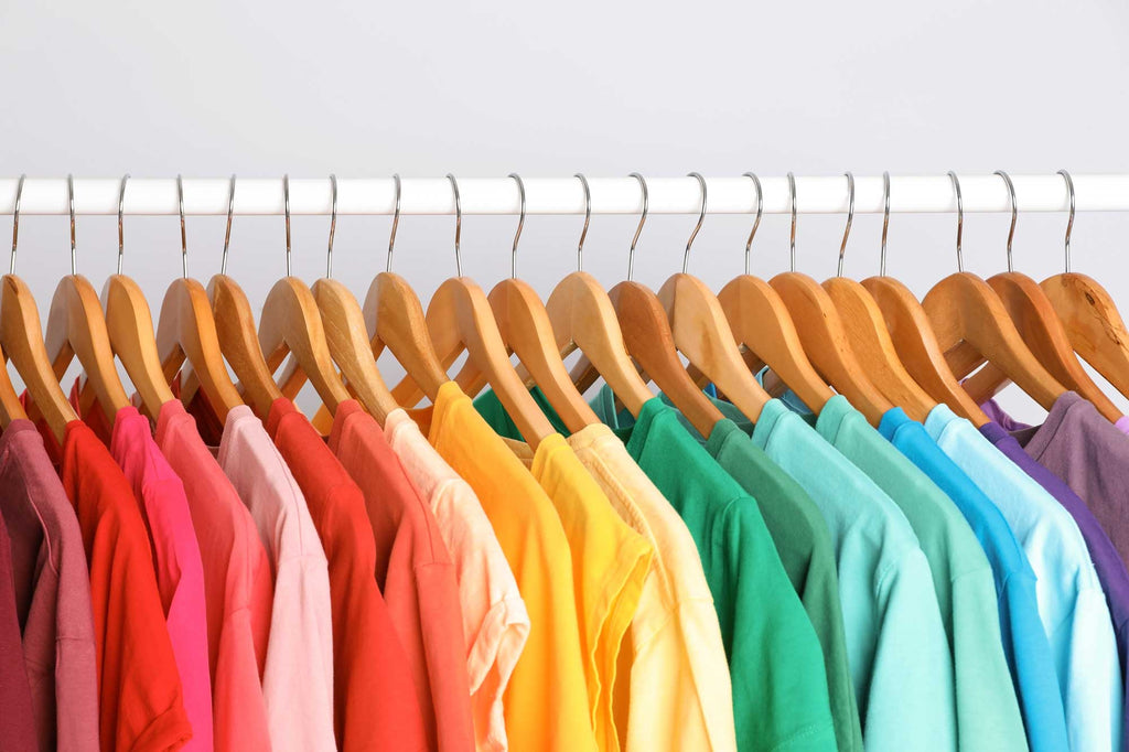 Brightly coloured Tshirts on wooden hangers, hanging on a rack