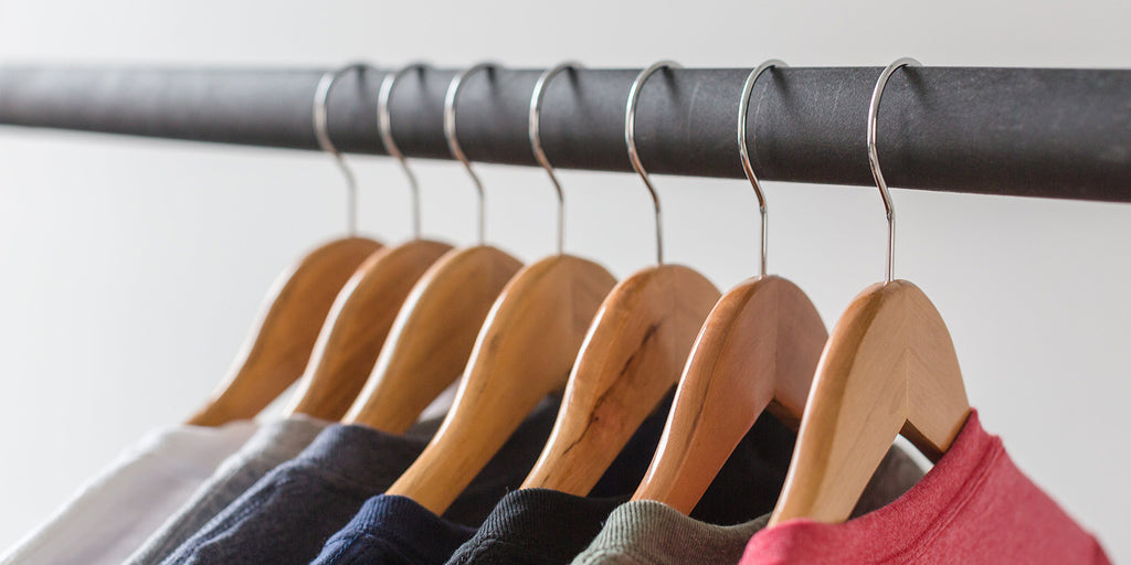 Close up shot of tshirts hanging on wooden hangers on a metal rack